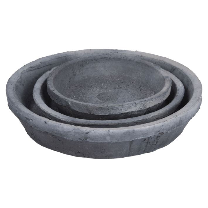 A trio of aged terracotta round flower pots and saucers in petite sizes are neatly stacked within each other. Their rough texture exudes the charming allure of aged terracotta, making them an ideal choice for a Tuscan-themed patio. These pots are displayed against a simple white background.